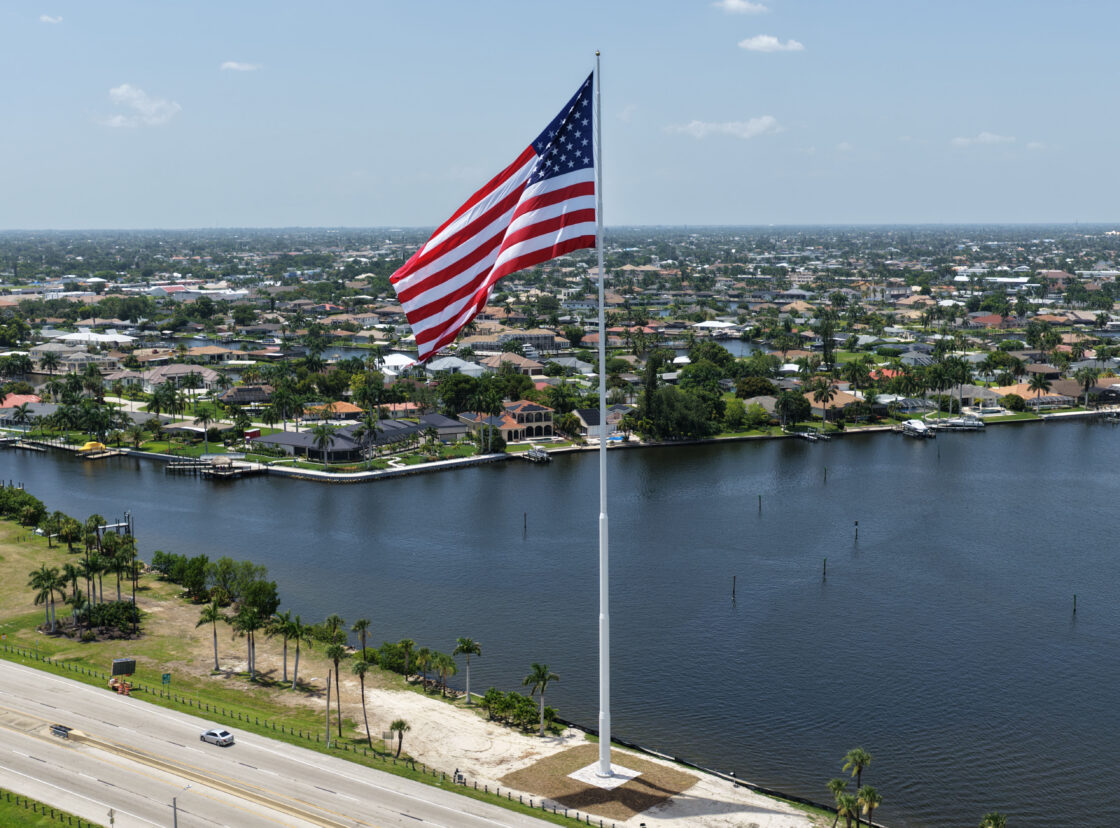 Large American flag over waterfront neighborhood